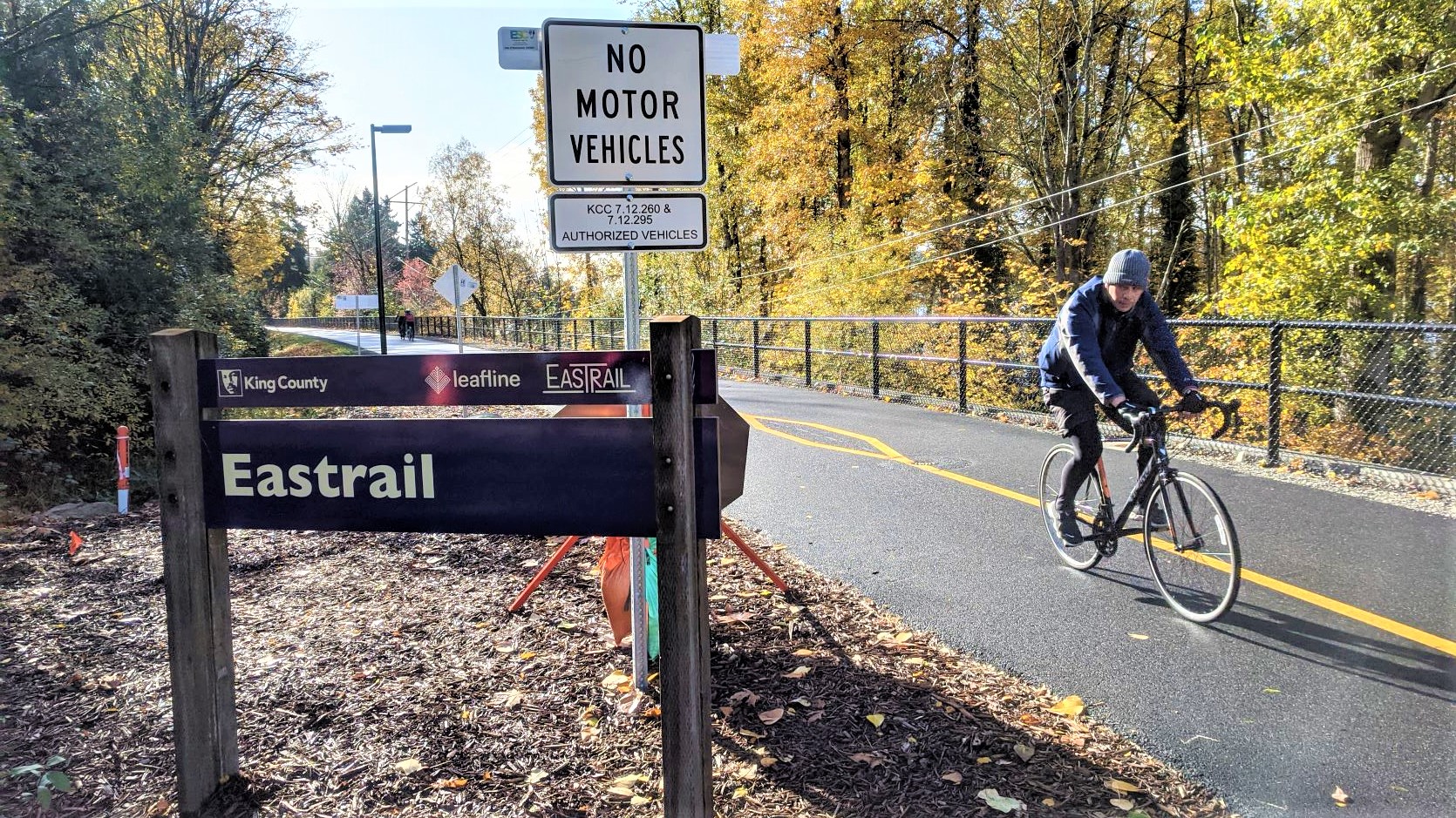 A person bikes past the Eastrail sign