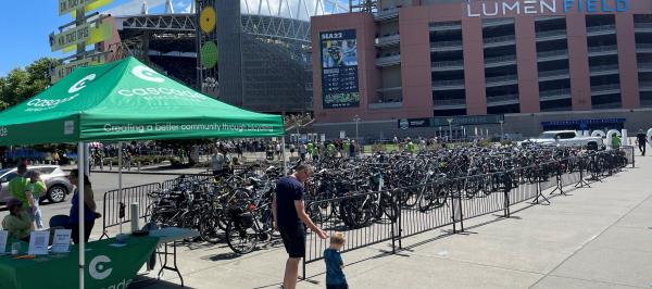 A father and son walk toward Lumen Field past the Cascade tent and rows of parked bikes